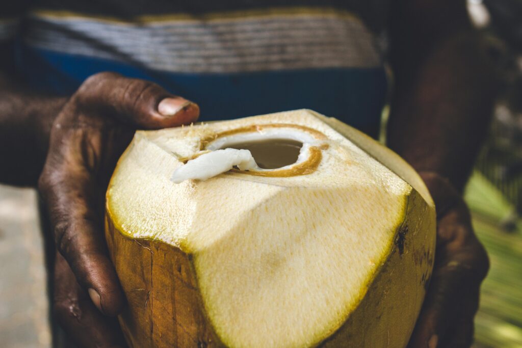 A fresh coconut being held, showcasing refreshment in a tropical setting.