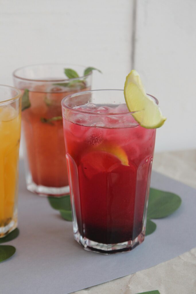 Three colorful iced beverages with citrus garnishes, perfect for cooling off.